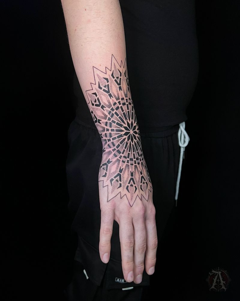 Tatuaje dotwork de mandala y puntillismo en muñeca y mano, en negro