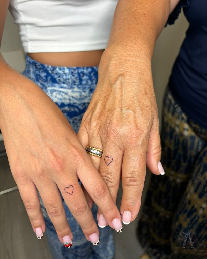 Tatuaje de corazones diminutos a juego en los dedos, fine line en negro y gris