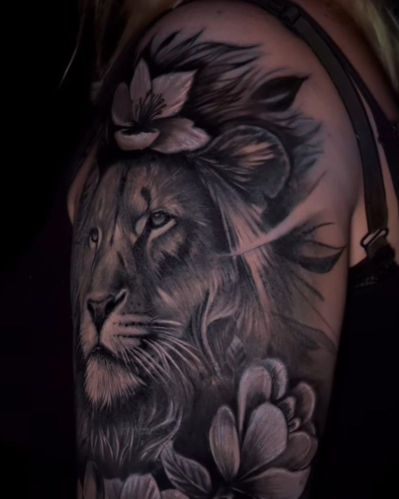 Tatuaje realista de un león rodeado de magnolias en el hombro, en negro y gris